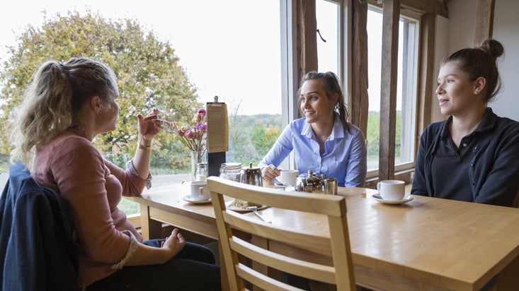 Three women sitting at a table in the cafe at Sissinghurst Castle Garden, Kent